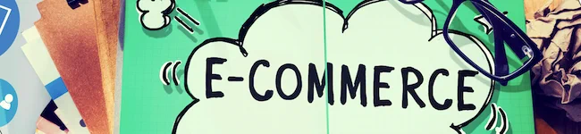 The word "e-commerce" on paper on a desk with design tools