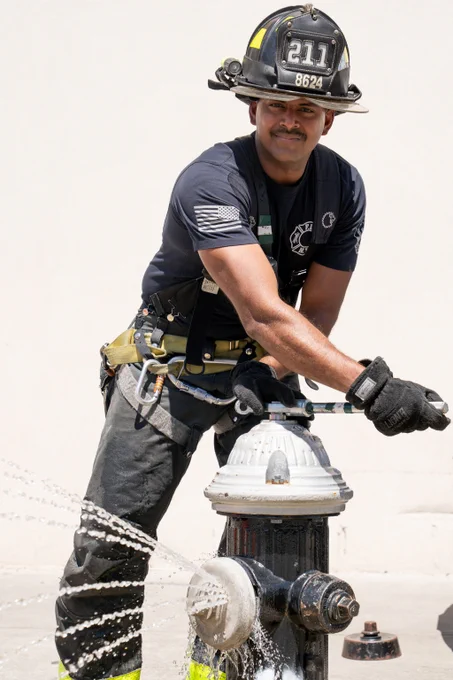 NYC Firefighter in full gear installing a spray cap on a fire hydrant.