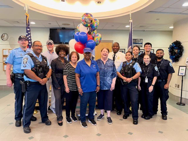 Members from the Four Seasons community in Dumfries standing next to members of the police department in the lobby of the eastern district station