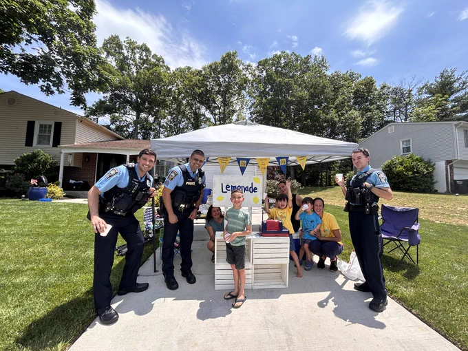 Members of the police department standing with Alex's family at their lemonade stand