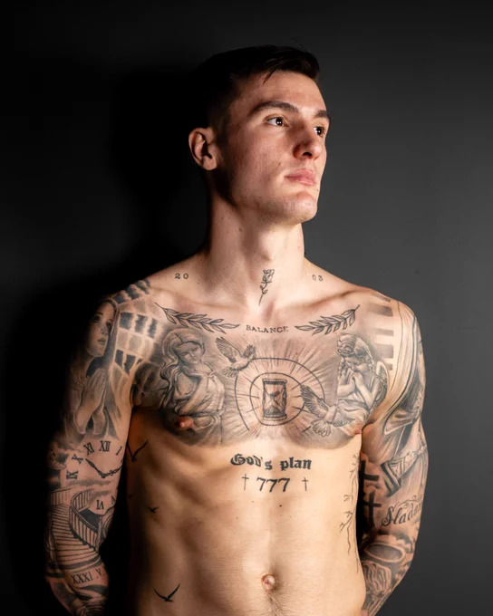 Benjamin Sesko poses topless to show his body art, before an interview about his tattoos.