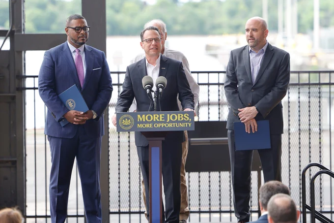 Governor Josh Shapiro speaks from a podium with a sign reading 'More Jobs, More Opportunity' during an outdoor press event.
PA