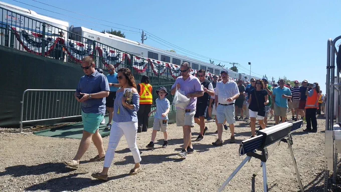 People walking down the platform after exiting an LIRR train at Shinnecock Hills station on a sunny day in 2018.