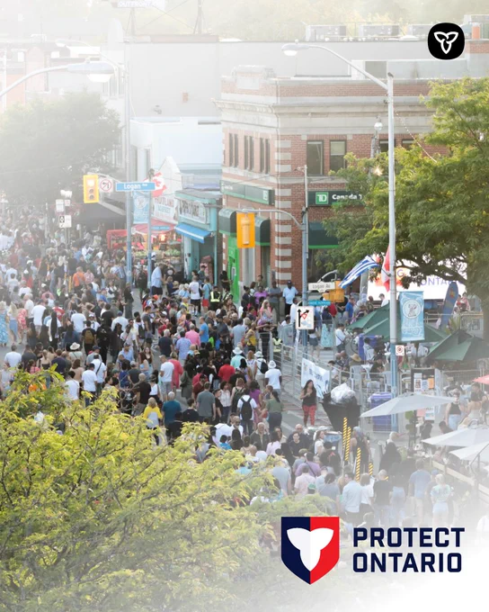 A large crowd fills a city street lined with shops and trees during an outdoor festival, viewed from above. The Protect Ontario logo appears in the corner.