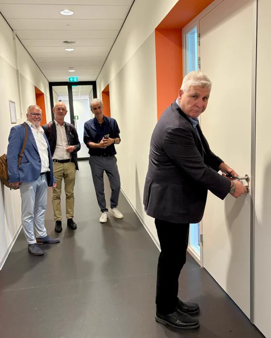 Ofer Vicus is unlocking an office door. Eric Appelman, Jan Lemmens, and Grennes Quee from Brightlands stand in the hallway.