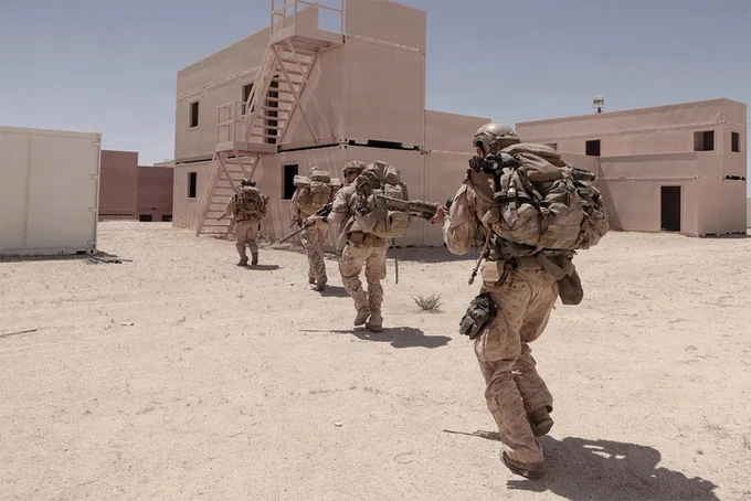 Marines move toward a multi-story training structure while conducting a patrol during urban operations training.