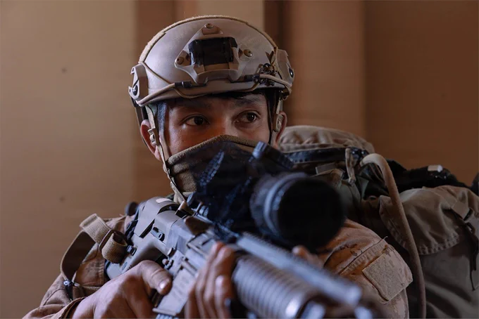 A Marine maintains security with a rifle inside a building during close-quarters training.