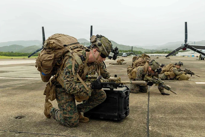 Marines establish security positions and prepare equipment beside MV-22B Ospreys during expeditionary training.