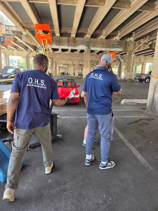 A photo of the Office of Homeless Services Housing Initiative Specialist team handing water to a person under a bridge during a street encounter. 