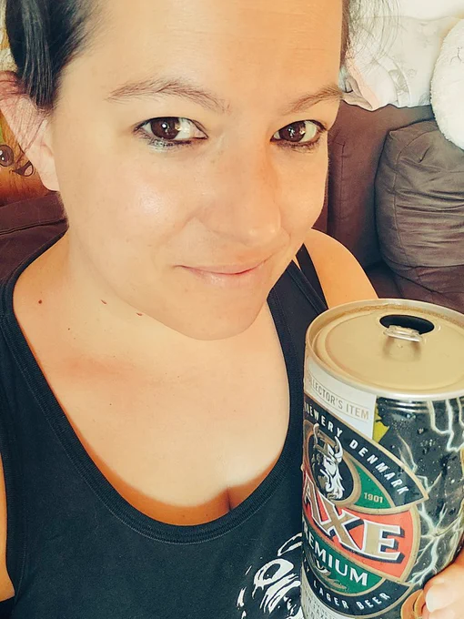 Ich schaue direkt in die Kamera, lächle dabei. Ich habe braune Augen, sie sind dezent geschminkt. Meine Haare sind zusammengebunden. 
Ich trage ein Tank-Top. Gwendoline's Kopf ist darauf zu sehen (Die Ärzte-Tank-Top).
In der Hand halte ich ein FAXE Bier. 