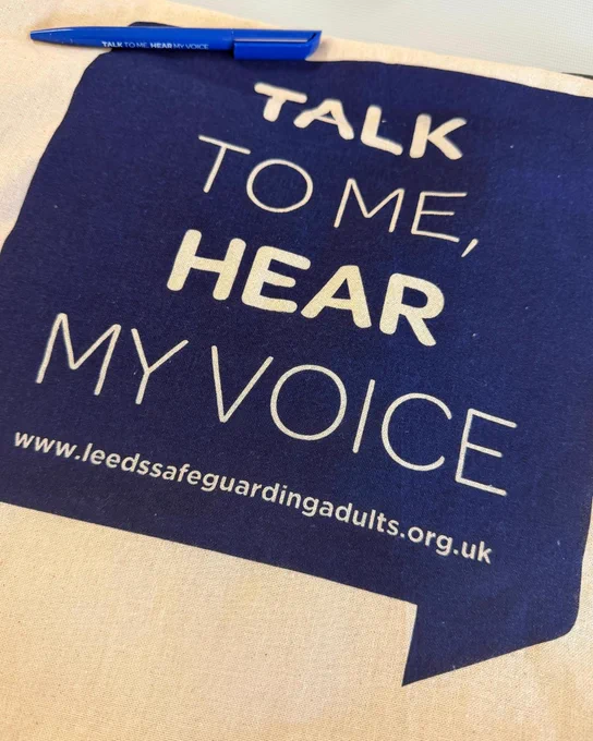 'Talk to me, Hear my voice' Leeds Safeguarding Adults Board-branded tote bag with a blue biro in the top left corner.