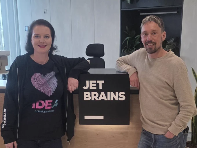 Marit van Dijk and Ronald Dehuysser both leaning on a JetBrains sign.