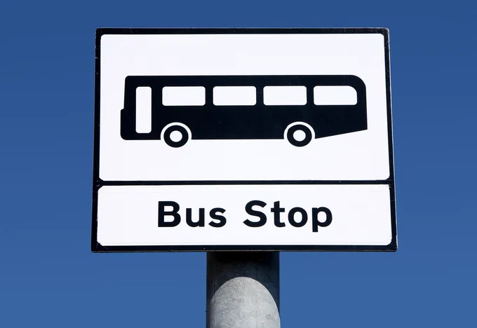 A bus stop sign with a bus icon and the words "Bus Stop" on a blue sky background.