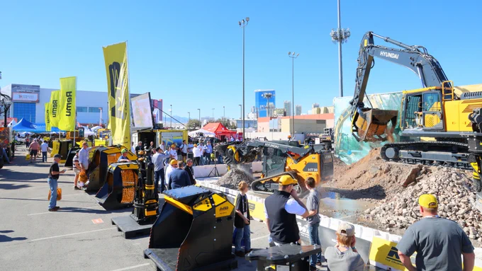 Large groups of people standing around exhibiter booths, construction equipment and large cranes digging in the dirt at CONEXPO-CON/AG 2026.