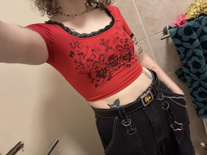 A picture of my body in black trip pants and a red cropped tshirt with black frills around its neckline