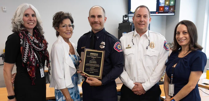 Five men and women stand together for photo. One is Engineer-Paramedic Hall, who holds his EMCT of the Year plaque.