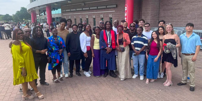 Family members and a new graduate posing outside the Alamodome.