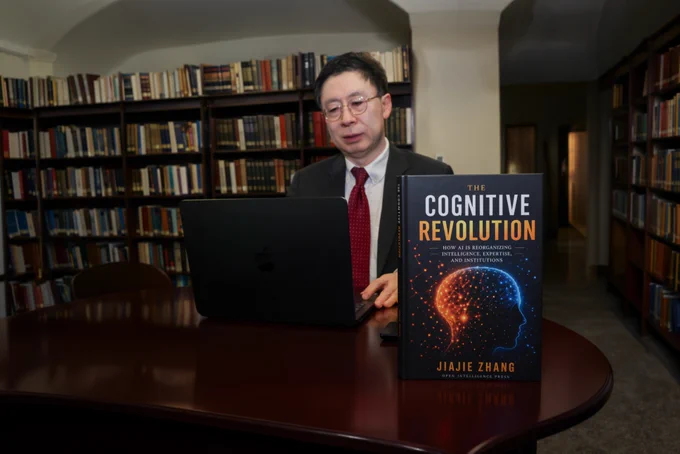 A person sitting at a table in a library, working on a laptop. A book titled "The Cognitive Revolution" by Jiajie Zhang is prominently displayed on the table.