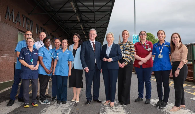 Image of 13 people standing in a row - First Minister Michelle O’Neill, deputy First Minister Emma Little-Pengelly, and Health Minister Mike Nesbitt with staff from the Mater Hospital.

