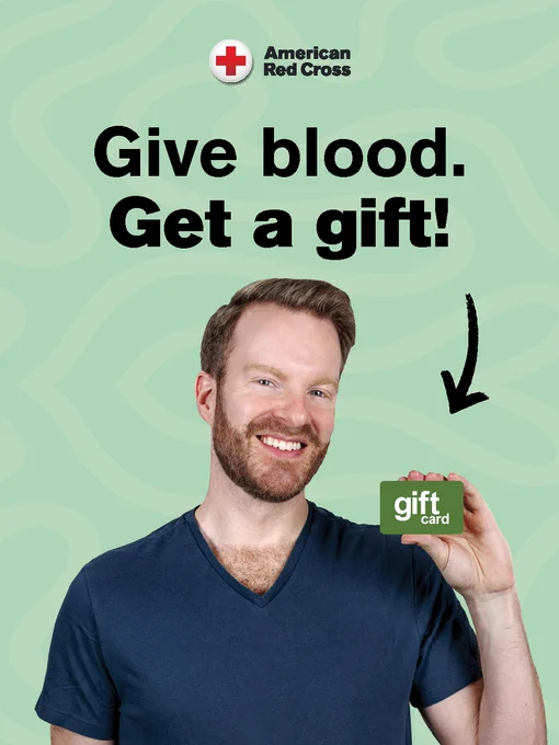A person with a beard smiles while holding a gift card. Text reads "Give blood. Get a gift!" The American Red Cross logo is at the top.