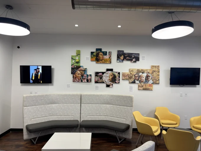 Modern lounge area with photos on the wall above a curved gray sofa, yellow armchairs, and a white coffee table.