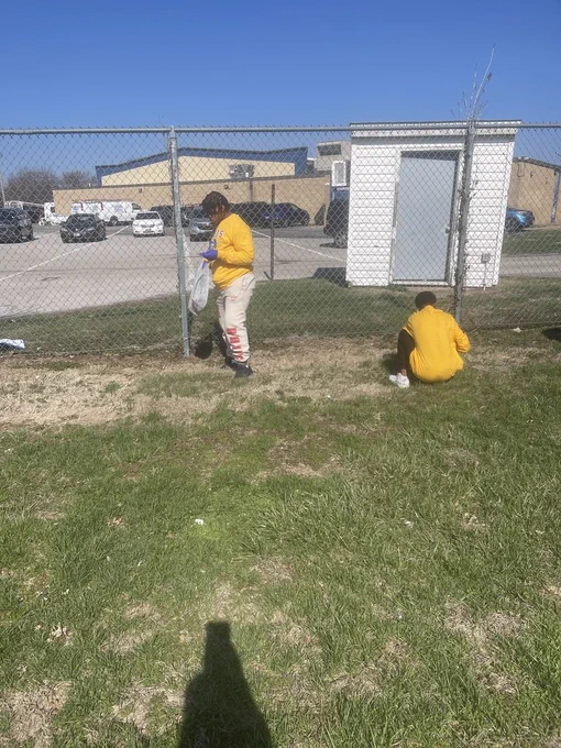 students picking up trash from area near the football field
