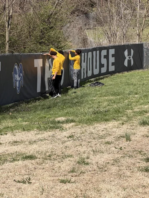 students reattach the banner on the Riverview Gardens High School baseball/softball field