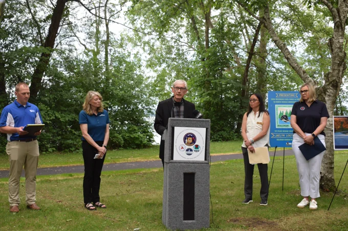 Gov. Evers speaks from a podium with cabinet secretaries at Lake Kegonsa State Park 