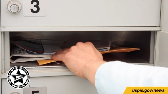 Hand retrieving mail from a cluster mailbox. The U.S. Postal Inspection Service logo appears in the bottom left corner.