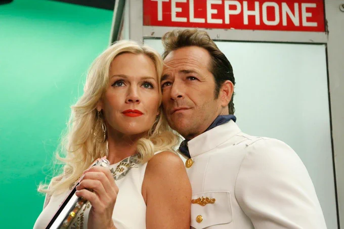  This image shows actors Luke Perry and Jennie Garth in a scene from the TV show Community.

Luke Perry guest-starred as a character named Inspector Spacetime in a 2013 episode. Jennie Garth appeared alongside him in a parody US version of Doctor Who.
