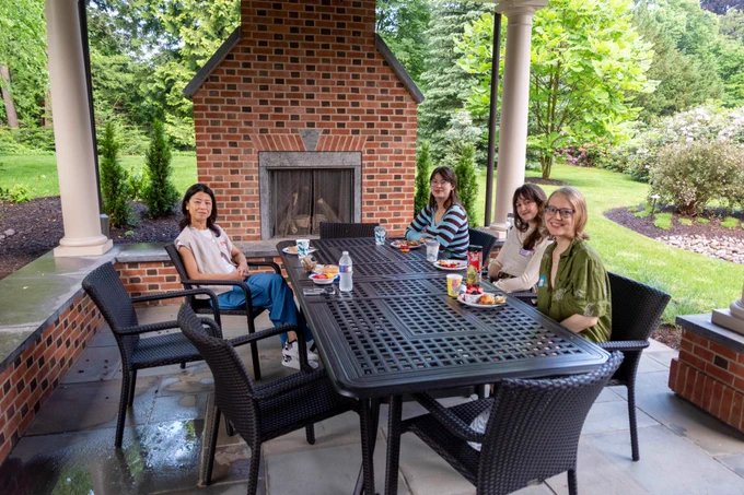 Women sitting around a table in front of an outdoor fireplace  