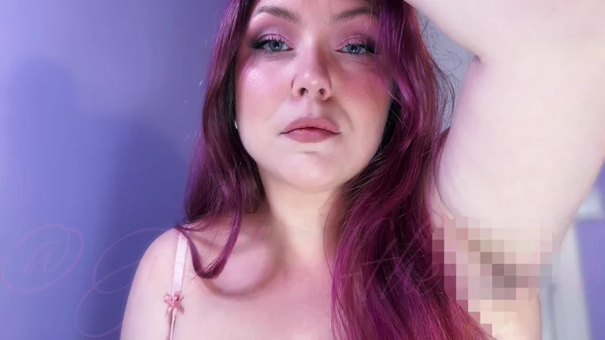 Goddess Åse from Her chest up. One arm up and hand in Her vibrant pink hair. Her armpit is censored with pixels. Her face is beautifully made up in shades of pink, and She looks down at you with Her piercing blue eyes