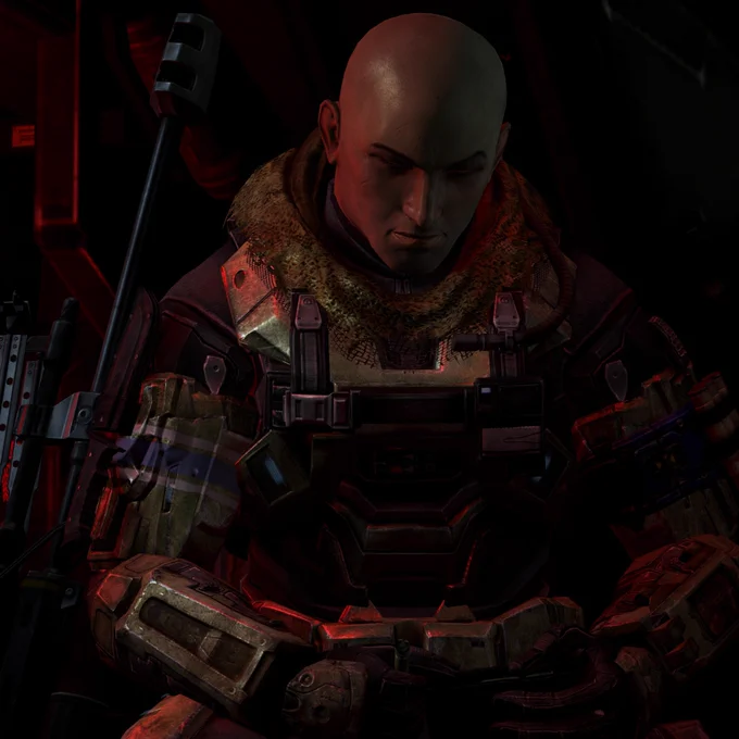 A bald figure dressed in futuristic armor sits in a dark, red-lit environment. The armor has mechanical detailing and a textured collar. Weapons are visible in the background, adding to the intense atmosphere.