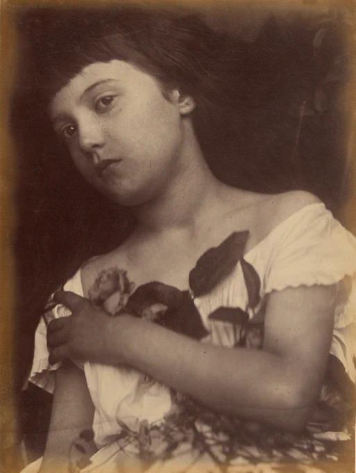 Portrait of a child posing with a rose stem with the leaves attached. She holds the rose in place with one arm folded across her chest.