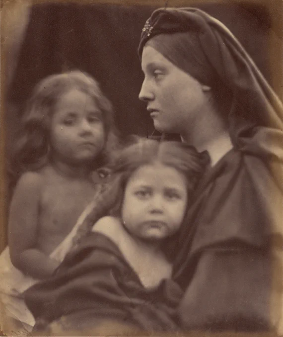 Side profile of a young woman with two children, both of whom stare directly at the camera.