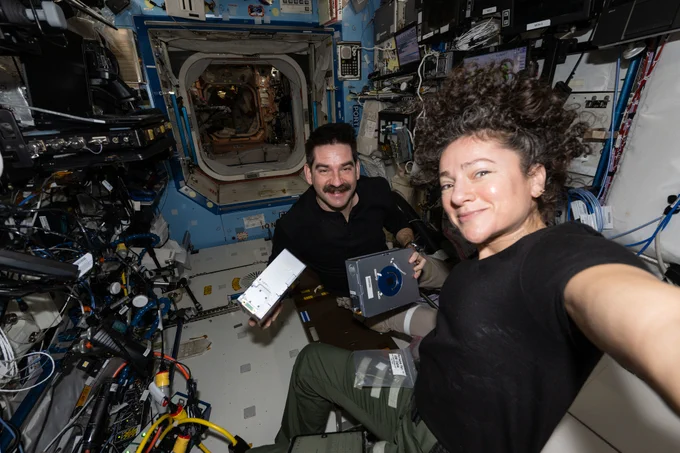 NASA astronauts Jack Hathaway and Jessica Meir, both Expedition 74 flight engineers, pose together as Hathaway shows off a pair of Advanced Space Experiment Sample Processor-4 cassettes being used aboard the International Space Station to study how weightlessness affects drug crystals possibly leading to new pharmaceutical formulas.