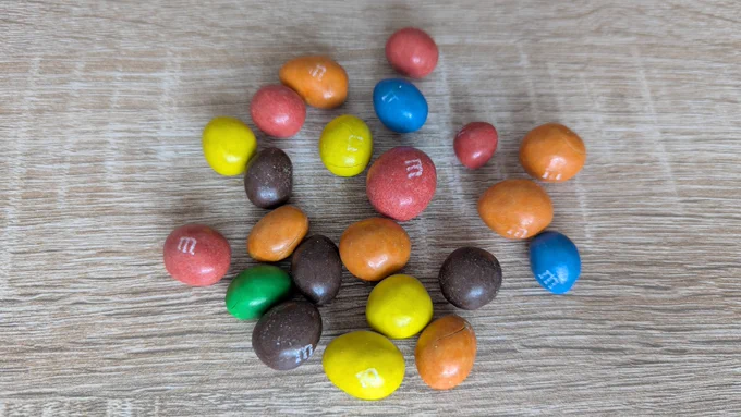 Bunte M&M‘s auf einer eichefarbenen Tischplatte.