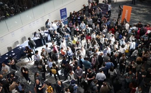 Large crowd of people gathered in a spacious indoor venue, engaging in conversations and networking activities.