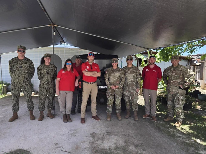 A group of personnel in uniforms and red USACE shirts pose for a group photo