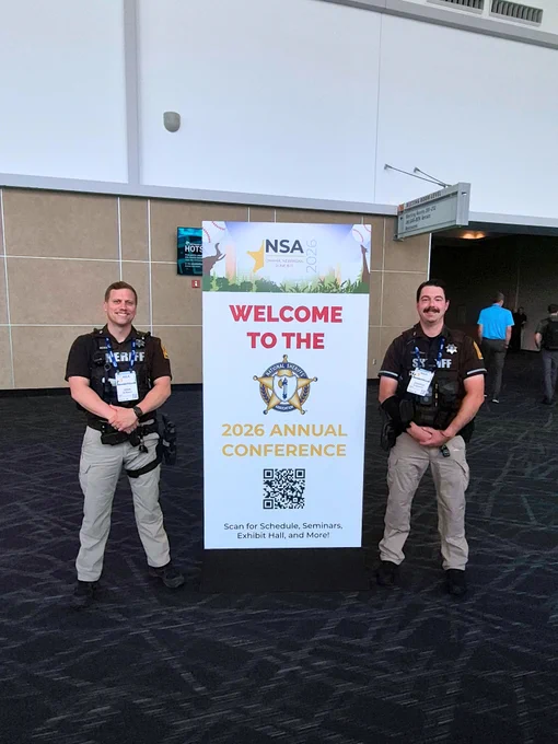 Deputies in uniform standing next to a Welcome to the 2026 Annual Conference sign.