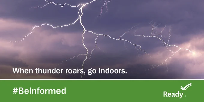 Bright lightning bolts streak across a dark, stormy sky with a safety message urging people to go indoors during thunder.