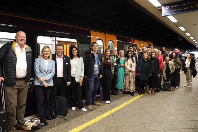 Group photo of rail colleagues standing in front of a train at Birmingham New Street station.