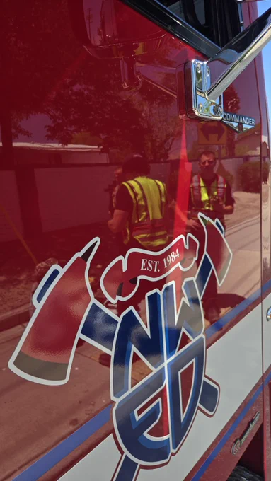 A fire crew is seen in the reflection of a fire engine door
