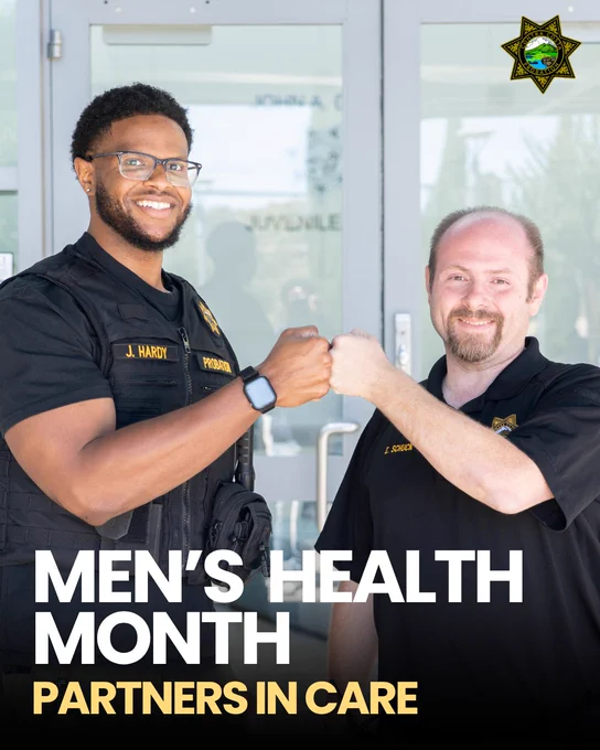 Two men in uniform fist-bump and smile outside a building, symbolizing teamwork. Text reads "Men's Health Month: Partners in Care". 