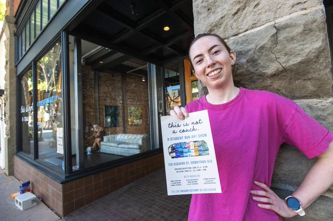 Art student holding up the flyer outside the art studio in downtown San Luis Obispo