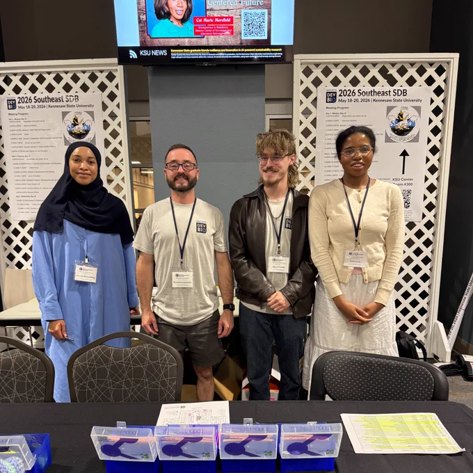 Doctor Brandon Carpenter, middle left, stands with Kennesaw State students at the SESDB meeting check-in table at the KSU Center.