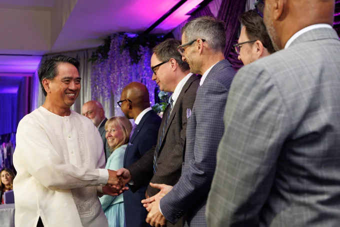A LLUH employee is smiling while walking across the stage shaking hands. 