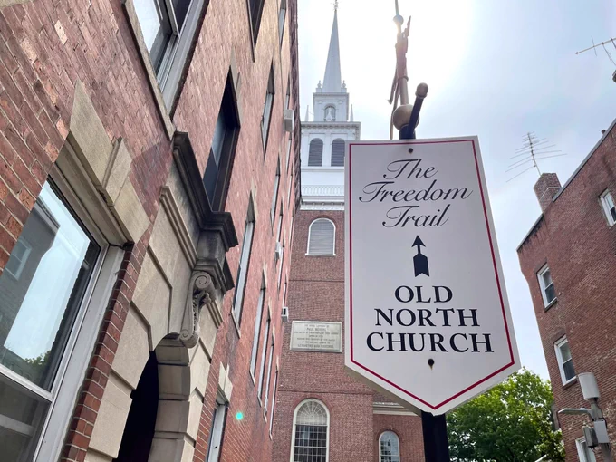 Foreground: A Freedom Trail sign pointing at the Old North Church.
Background: The steeple of the Old North Church.  

