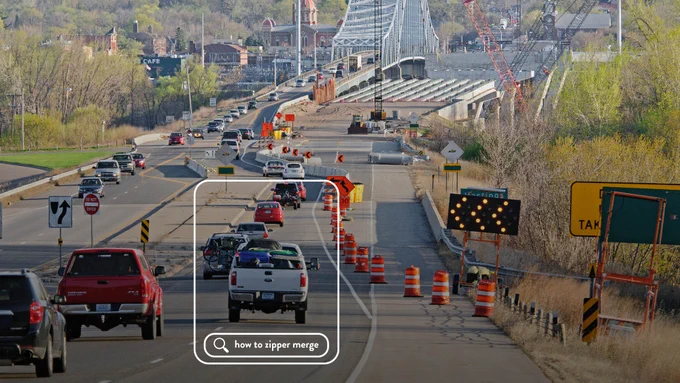 Traffic on a highway approaching a construction zone near a bridge, with vehicles beginning to zipper merge. A search overlay with the text “how to zipper merge” is visible.