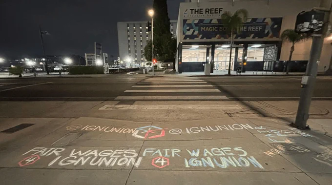 Chalk graffiti reading "Fair wages 4 IGN Union" outside The Reef in LA  
